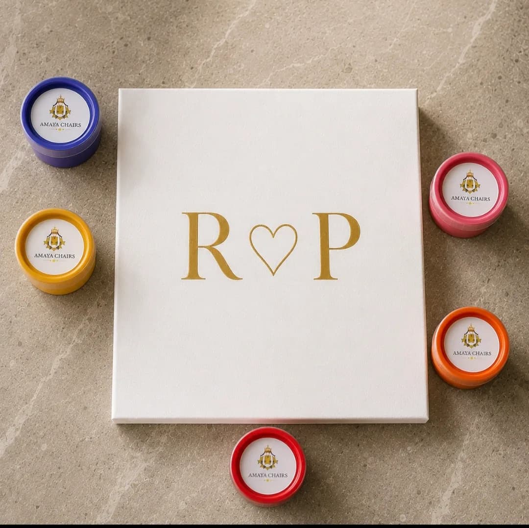 A Maiyan board printed with the initials “R ♥ P” in gold, set among pots of rangoli colours.