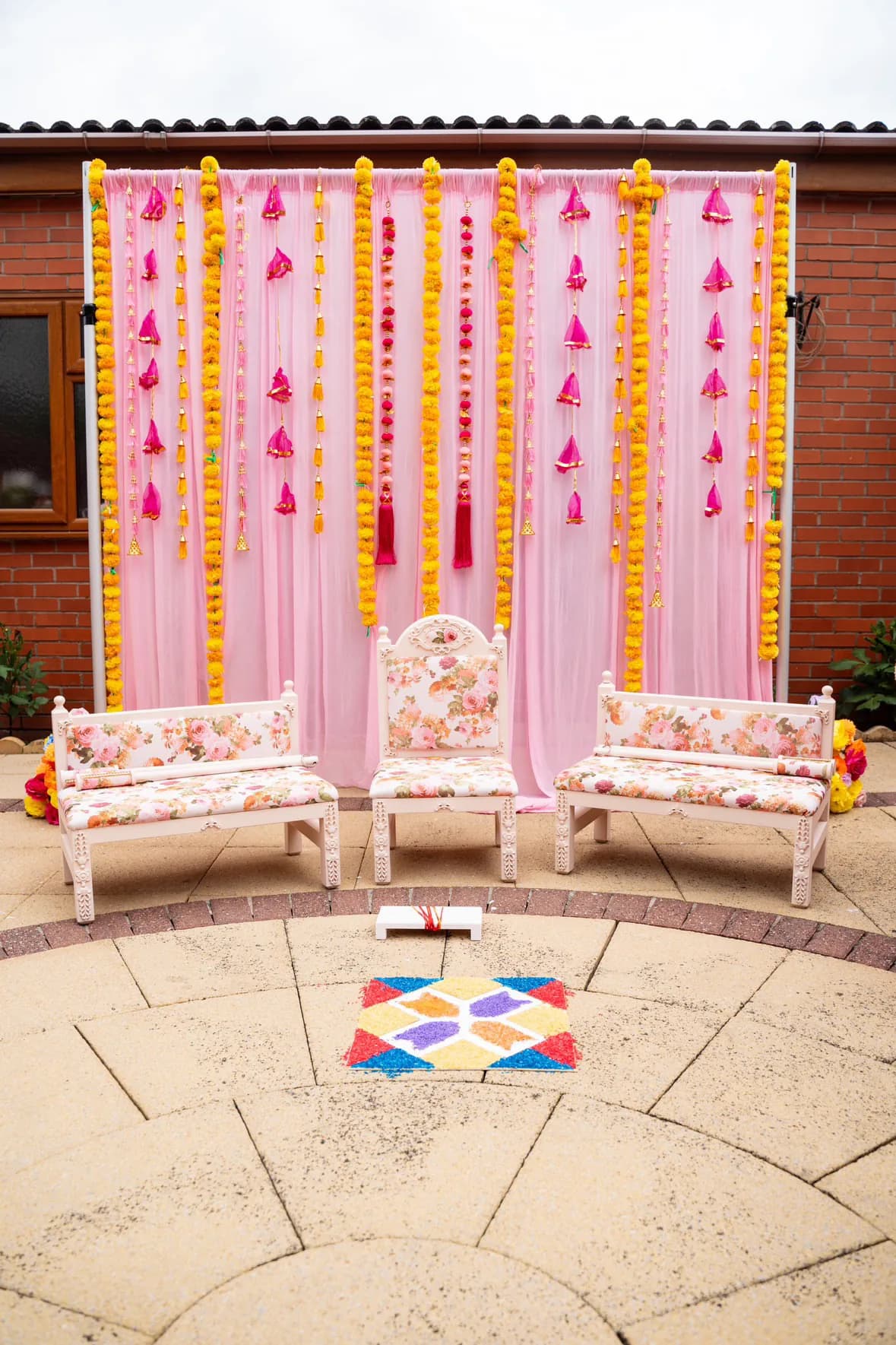 The Enchantress suite on a circular paved patio, backed by pink tassels and marigold garlands.