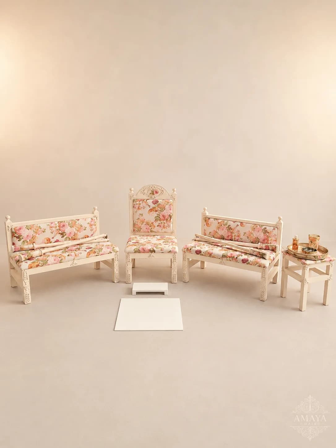 The Enchantress Maiyan suite on an ivory backdrop: a carved cream head chair with a shaped crest between two matching side benches, all upholstered in a soft rose floral print.