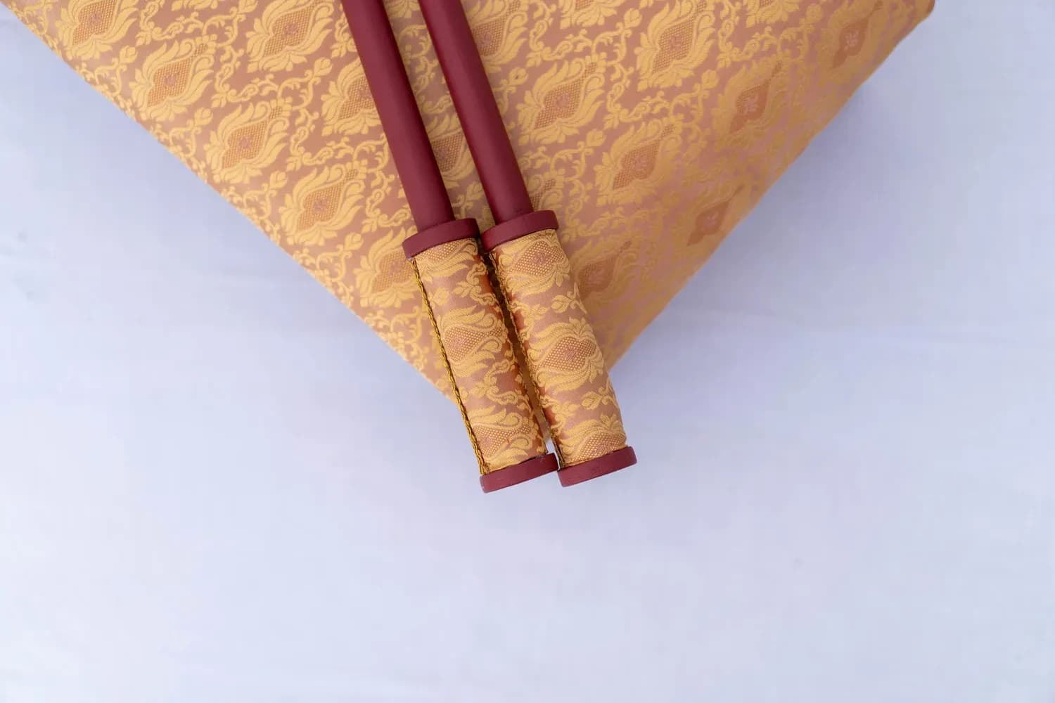 Chunni sticks resting on a Peaches & Wine brocade bolster.