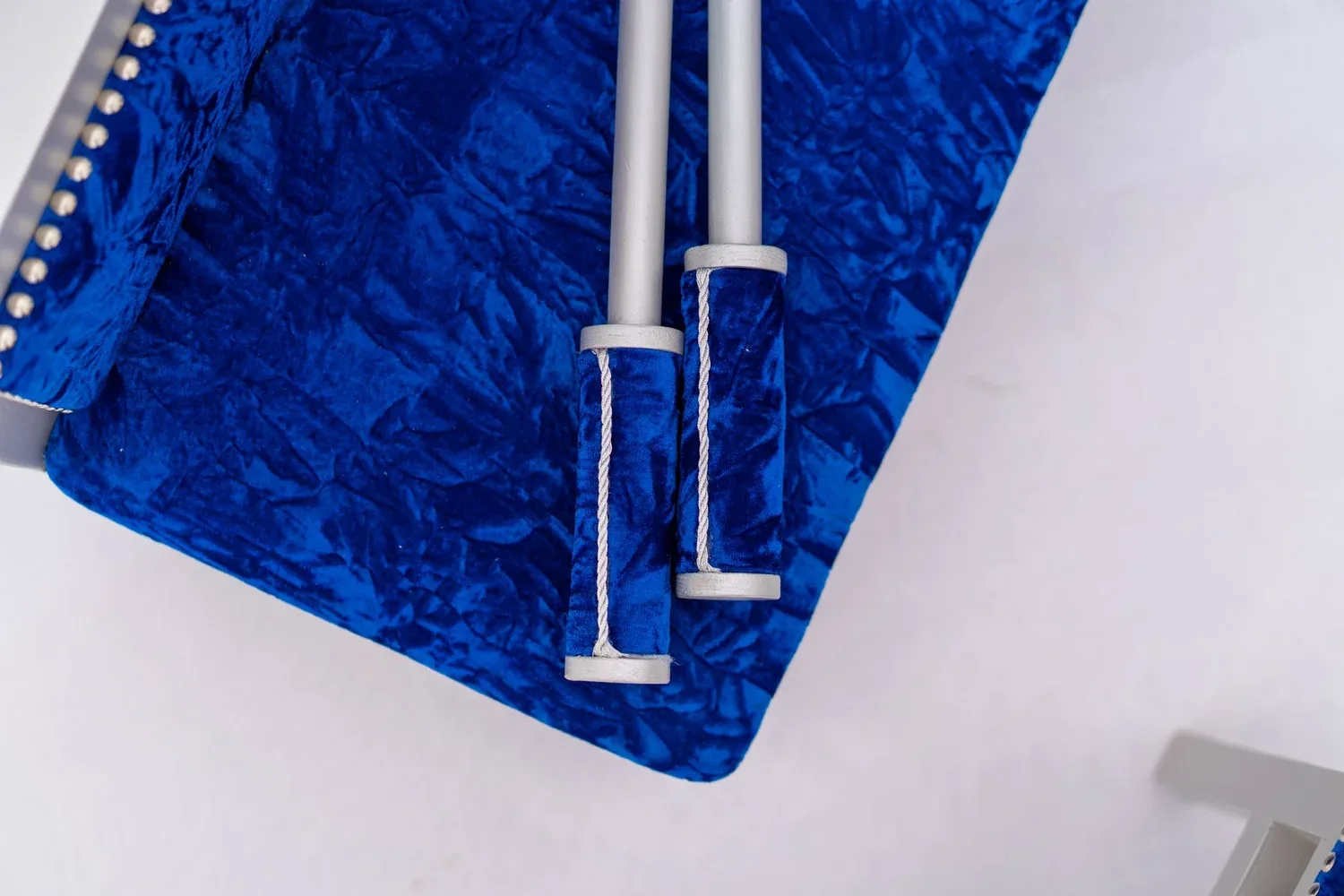 Chunni sticks laid across a royal blue velvet bolster on a Blue Prince bench.
