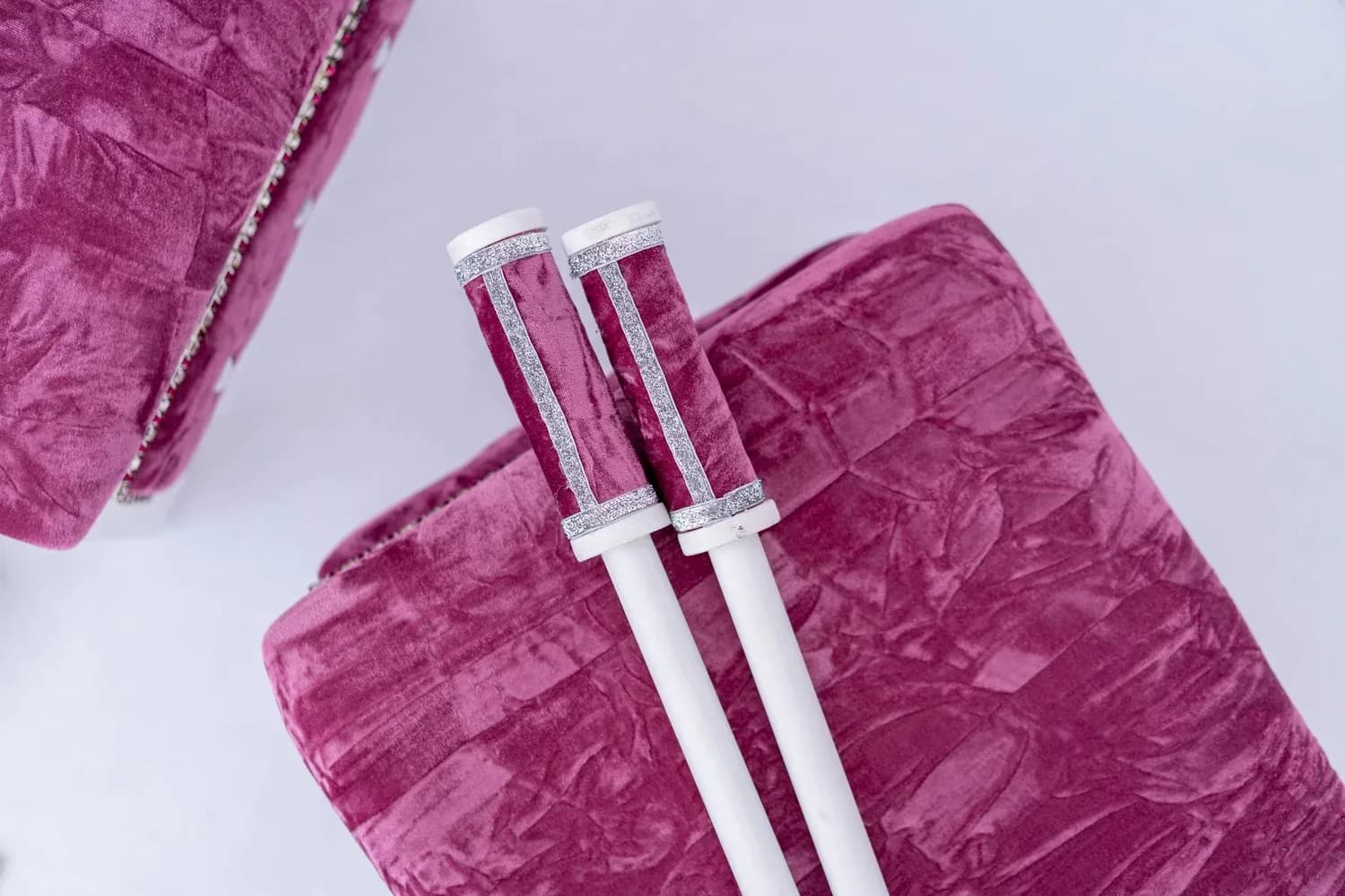 Chunni sticks laid across a Rose Quartz bolster in magenta crushed velvet.