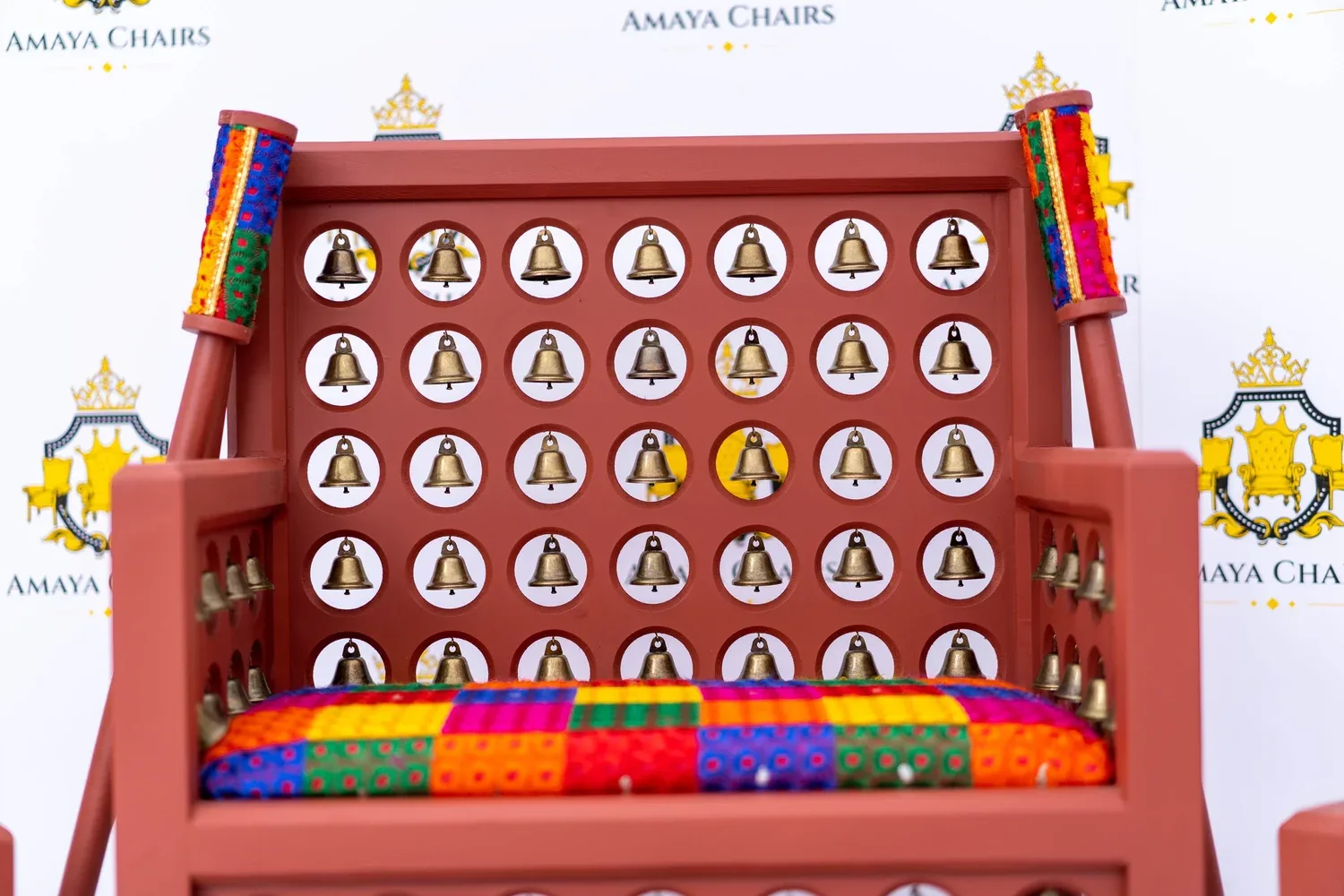 The Satrang head chair showing the terracotta frame, brass bell detailing and multicoloured seat.