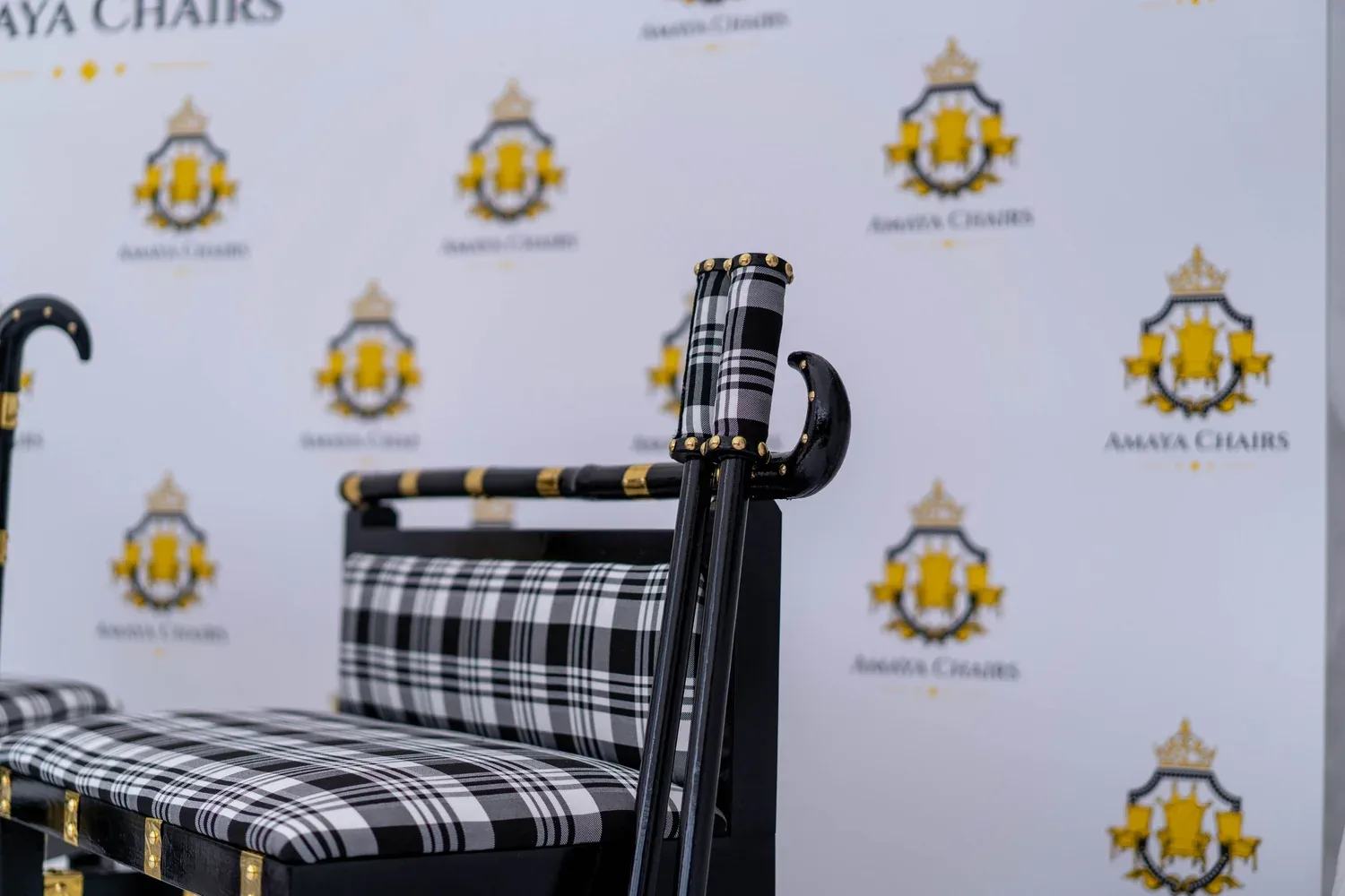 The Gabru head chair seen from the front, showing the gold-banded black frame and monochrome check seat pad.