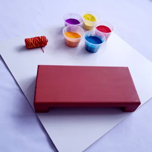 A keepsake board laid out with pots of ceremony colours and a spool of red thread, ready for handprints.