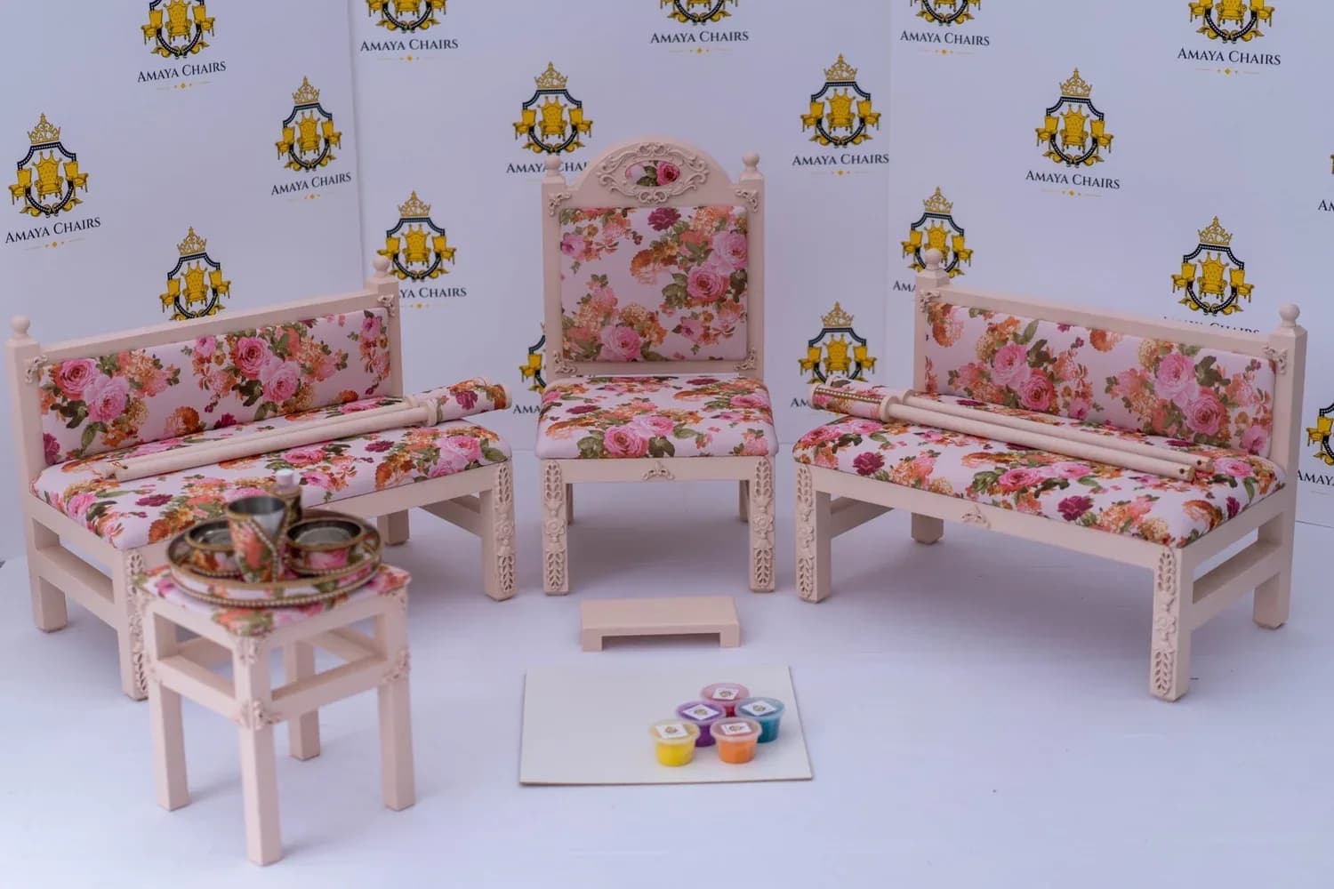 The Enchantress suite photographed in full: carved cream head chair between two matching benches, all in the rose floral print.